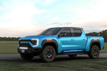 A bright blue Nikola pick-up truck parked on a rural road with a grassy landscape in the background